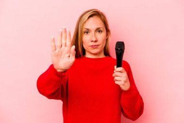 Pembe arka planda izole edilmiş genç beyaz kadın elini uzatmış, dur işareti göstererek seni engelliyor..
