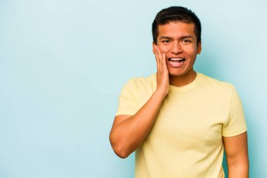 Mavi arka planda izole edilmiş genç bir İspanyol yüksek sesle bağırıyor, gözleri açık ve elleri gergin tutuyor..