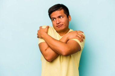 Genç İspanyol adam mavi arka planda yalnızdı. Kucaklaşma, kaygısız gülümseme ve mutluluk..