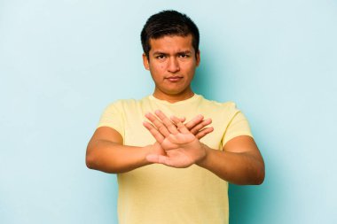 Mavi arka planda izole edilmiş genç İspanyol adam elini uzatmış, dur işareti göstererek seni engelliyor..