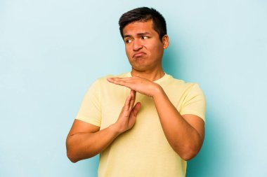 Mavi arka planda izole edilmiş genç İspanyol bir adam bir mola hareketi gösteriyor..