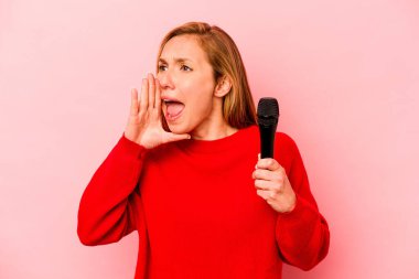 Pembe arka planda izole edilmiş genç beyaz kadın bağırıyor ve avuç içini açık tutuyor..