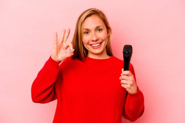 Beyaz tenli genç bir kadın pembe arka planda izole edilmiş neşeli ve kendinden emin..