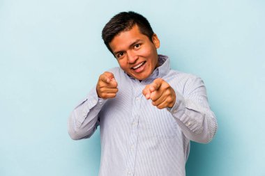 Mavi arka planda izole edilmiş genç İspanyol adam. Önü gösteren neşeli gülücükler..