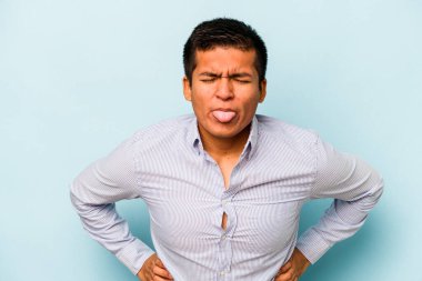 Genç İspanyol adam mavi arka planda izole edilmiş komik ve dost canlısı bir dil uzatıyor..