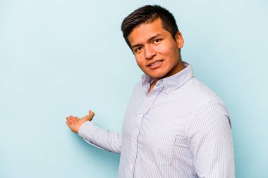 Mavi arka planda izole edilmiş genç bir İspanyol hoş geldin ifadesi sergiliyor..