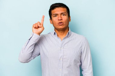 Mavi arka planda izole edilmiş genç bir İspanyol ağzı açık bir şekilde üst tarafı işaret ediyor..