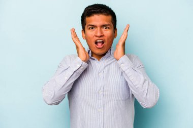 Genç İspanyol adam mavi arka planda izole edildi. Şaşırdı ve şok oldu..