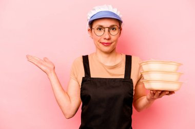 Pembe arka planda izole edilmiş genç aşçı kadın bir avuç içinde fotokopi alanı ve belinde bir el daha olduğunu gösteriyor..