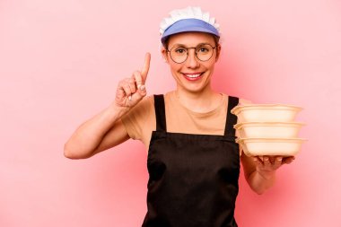 Genç aşçı gönüllü kadın pembe arka planda izole edildi..