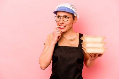 Genç aşçı gönüllü kadın pembe arka planda izole edilmiş rahatlamış fotokopi odasına bakan bir şey düşünüyor..