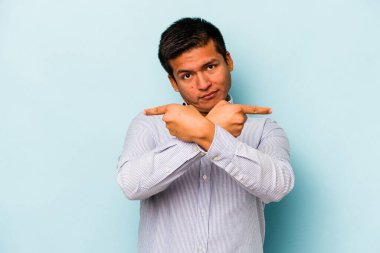 Mavi arka plan noktalarında izole edilmiş genç İspanyol adam iki seçenek arasında seçim yapmaya çalışıyor..