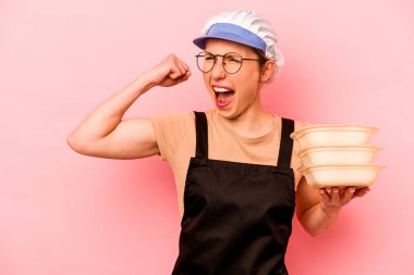 Genç aşçı gönüllü kadın pembe arka planda izole edilmiş zafer sonrası yumruğunu kaldırıyor, kazanan konsept..