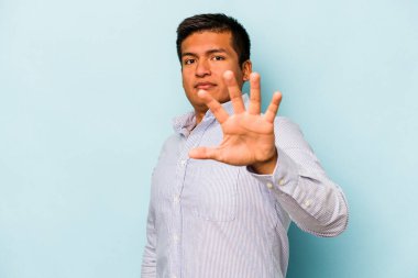 Genç İspanyol bir adam mavi arka planda izole edilmiş. Yakın bir tehlike nedeniyle şok oluyor.