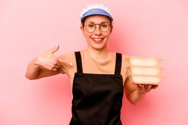 Genç aşçı, pembe arka planda izole edilmiş, gömleğin fotokopi odasını gösteren, gururlu ve kendinden emin bir gönüllü kadın.