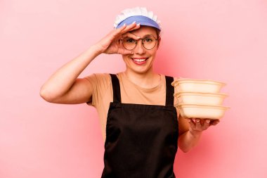 Genç aşçı, pembe arka planda izole edilmiş, gönüllü bir kadın heyecanlı..