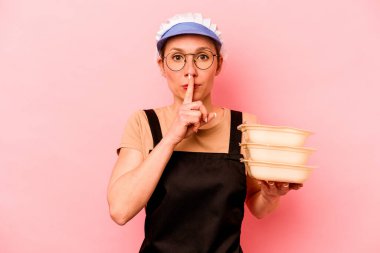 Genç aşçı gönüllü kadın pembe arka planda izole edilmiş ya sır saklıyor ya da sessizlik istiyor..