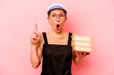Genç aşçı gönüllü kadın pembe arka planda izole edilmiş. Harika bir fikri var, yaratıcılık kavramı..