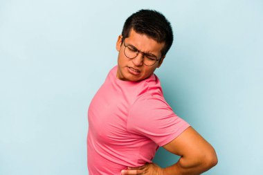Genç İspanyol bir adam mavi arka planda izole edilmiş sırt ağrısı çekiyor..