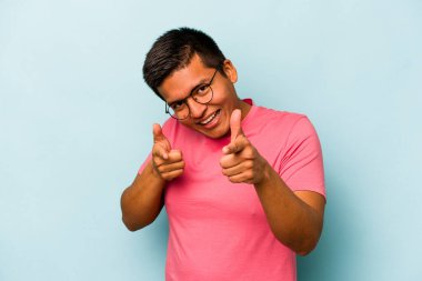 Mavi arka planda izole edilmiş genç İspanyol adam parmaklarıyla öne işaret ediyor..