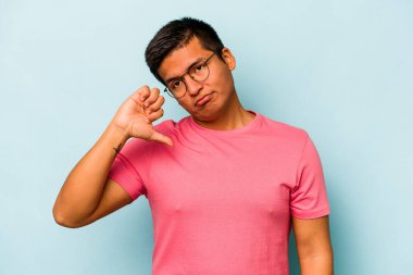 Genç İspanyol bir adam mavi arka planda izole edilmiş. Hoşlanmadığı bir hareket gösteriyor. Anlaşmazlık konsepti.
