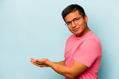 Mavi arka planda izole edilmiş genç İspanyol bir adam avucunun içinde bir kopyasını tutuyor..