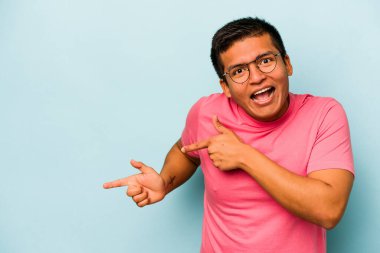 Mavi arka planda izole edilmiş genç bir İspanyol işaret parmaklarıyla işaret ederek heyecanlanıyor..