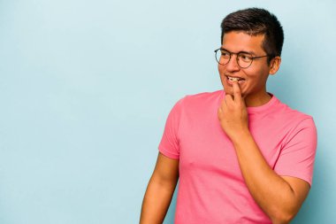 Mavi arka planda izole olmuş genç İspanyol bir adam rahatlamış bir şeyin fotokopi odasına baktığını düşünüyor..