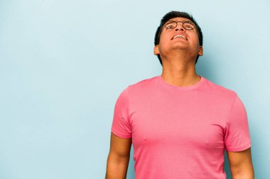 Genç İspanyol adam mavi arka planda izole edilmiş çok kızgın, öfkeli, hayal kırıklığına uğramış bağırıyor..