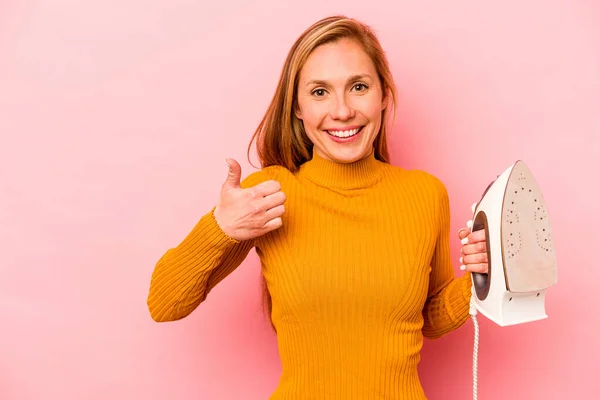 Joven Mujer Caucásica Sosteniendo Hierro Aislado Sobre Fondo Rosa Sonriendo —  Fotos de Stock