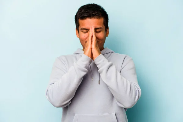 Молодий Іспаномовний Чоловік Ізольований Синьому Фоні Тримаючи Руки Молитві Біля — стокове фото