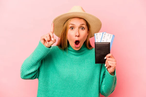 Pembe arka planda pasaport taşıyan beyaz bir kadın. Bir fikri, ilham verici bir konsepti var..