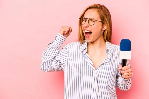 Kafkas TV sunucusu kadın pembe arka planda izole edilmiş zafer ve galibiyet kavramından sonra yumruğunu kaldırıyor..