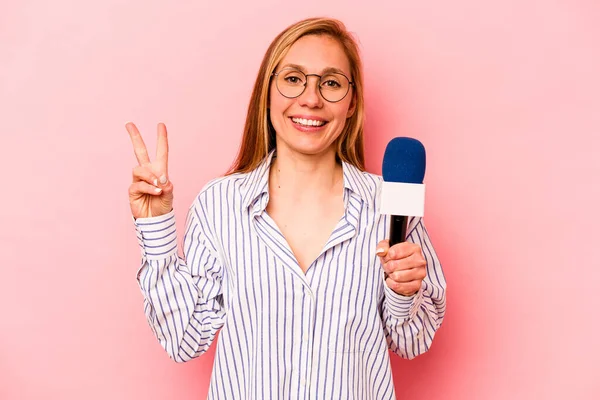 Kafkas TV sunucusu kadın pembe arka planda izole edilmiş neşeli ve kaygısız parmaklarıyla barış sembolü gösteriyor..