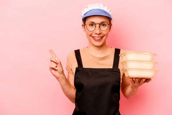 Jovem Cozinheira Voluntária Isolada Fundo Rosa Sorrindo Apontando Para Lado — Fotografia de Stock