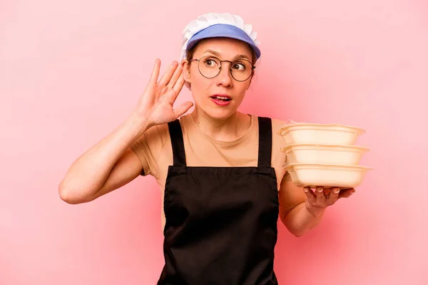 Jovem Cozinheira Voluntária Mulher Isolada Fundo Rosa Tentando Ouvir Uma — Fotografia de Stock