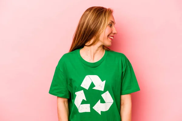 Young Volunteer Woman Isolated Pink Background Looks Aside Smiling Cheerful — стоковое фото