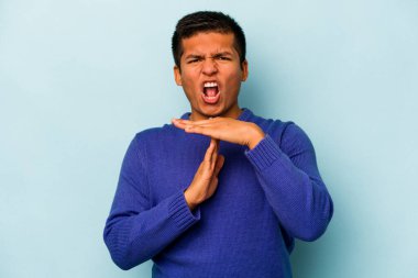 Mavi arka planda izole edilmiş genç İspanyol bir adam bir mola hareketi gösteriyor..