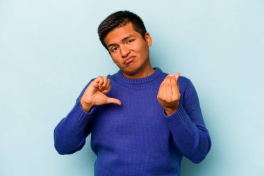 Genç İspanyol adam mavi arka planda izole edilmiş, parasız olduğunu gösteriyor..