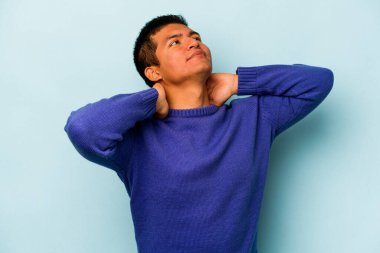 Genç İspanyol adam mavi arka planda izole edilmiş. Kendine güveniyor, elleri başının arkasında..