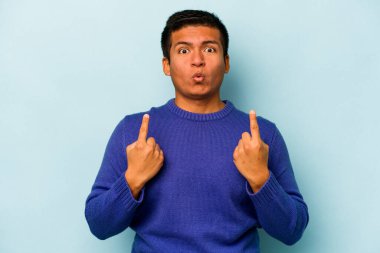 Mavi arka planda izole edilmiş genç bir İspanyol ağzı açık bir şekilde üst tarafı işaret ediyor..