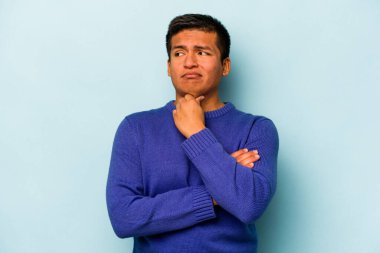 Mavi arka planda izole edilmiş genç İspanyol bir adam virüs ya da enfeksiyon yüzünden boğazında ağrı hissediyor..