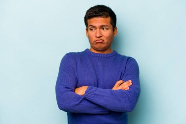 Genç İspanyol adam mavi arka planda izole edilmiş. Tekrarlanan bir görevden yorulmuş..