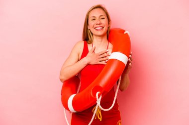 Pembe arka planda izole edilmiş beyaz kadın elini göğsünde tutarak kahkahalar atıyor..