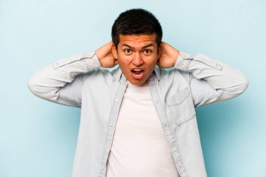 Genç İspanyol adam mavi arka planda izole edilmiş bağırıyor, çok heyecanlı, tutkulu, bir şeyden memnun..