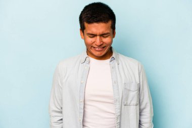 Mavi arka planda izole olmuş genç İspanyol adam gülüyor ve gözlerini kapıyor, rahatlamış ve mutlu hissediyor..