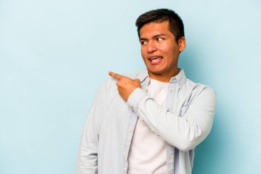Mavi arka planda soyutlanmış genç bir İspanyol gülümsüyor, neşeli ve keyifli görünüyor..