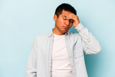 Genç İspanyol adam mavi arka planda izole edilmiş tapınaklara dokunuyor ve baş ağrısı çekiyor..