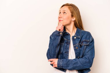 Beyaz arka planda soyutlanmış beyaz tenli genç bir kadın şüpheli ve şüpheci bir ifadeyle yana bakıyor..