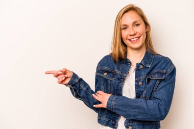 Beyaz arka planda izole edilmiş genç beyaz kadın işaret parmağıyla işaret ederek gülümsüyor..
